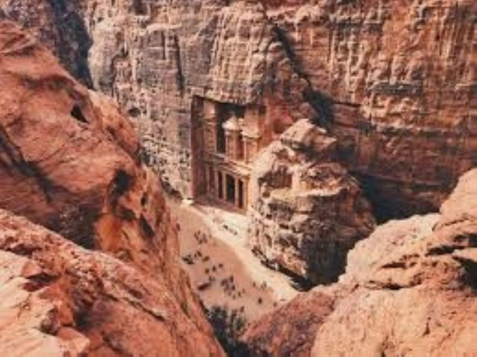 The Treasury at Petra seen from the ridge above, tiny figures on the sand below