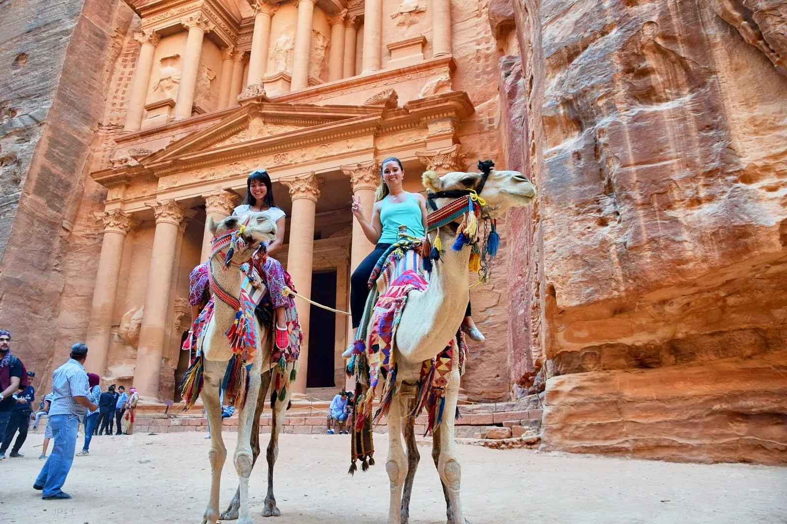 Two travellers on decorated camels in front of the Treasury at Petra